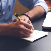 adulttale 主编林砚在编辑部工作台前整理互动叙事作品分支笔记的侧影，桌上摊开手写脉络草图，暖光台灯下的专注气氛